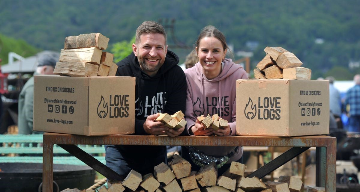 Heather and Paul, Love Logs founders, surrounded by logs and Love Logs cardboard boxes