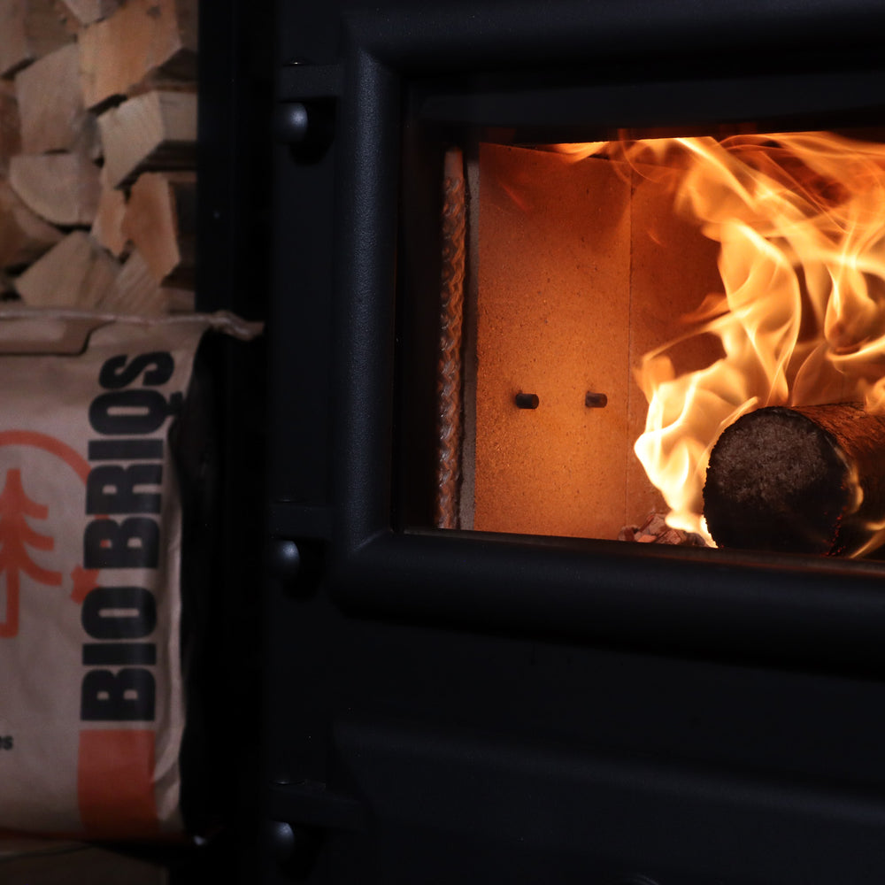 Bio Briqs firewood briquette on fire in log burner with bag in background