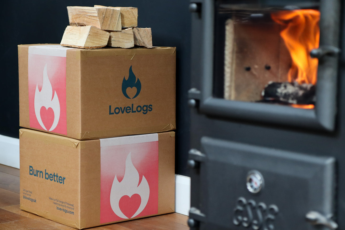 Fire inside a log burner with Love Logs kiln-dried firewood in background