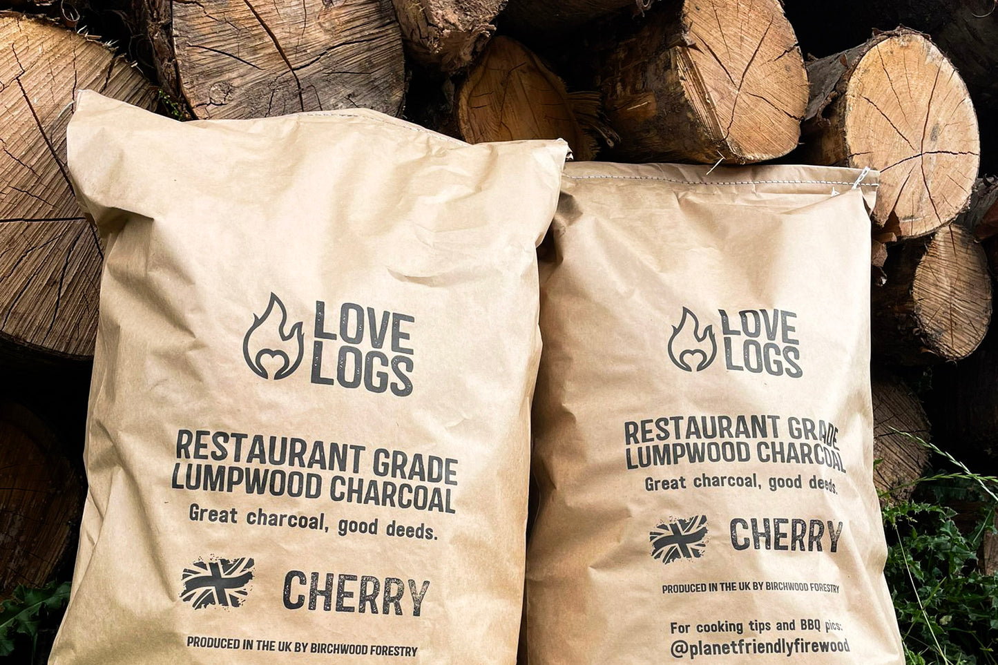 Love Logs Wild Cherry British Charcoal in front of cherry wood pile