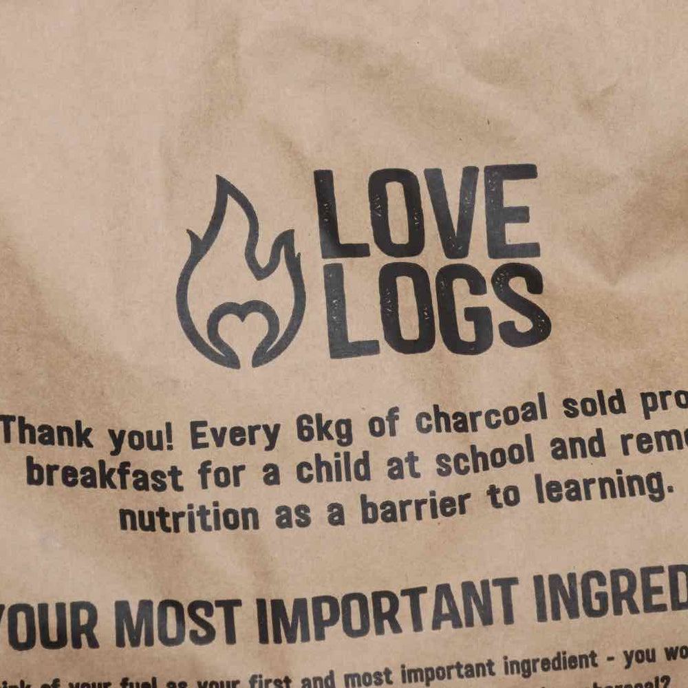 
                      
                        Close up of Love Logs British Charcoal bag which reads ' Thank you! Every 6kg of charcoal sold provides breakfast for a child at school and removes nutrition as a barrier to learning
                      
                    