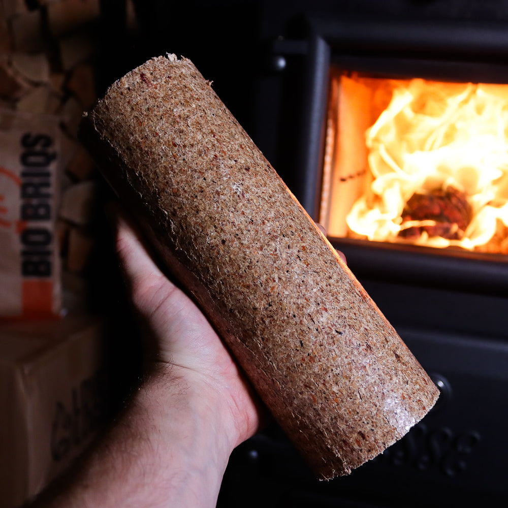 Bio Briqs firewood sawdust briquette in front of lit log burner