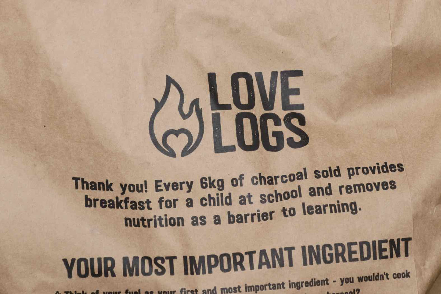 Close up of Love Logs British Charcoal bag which reads ' Thank you! Every 6kg of charcoal sold provides breakfast for a child at school and removes nutrition as a barrier to learning